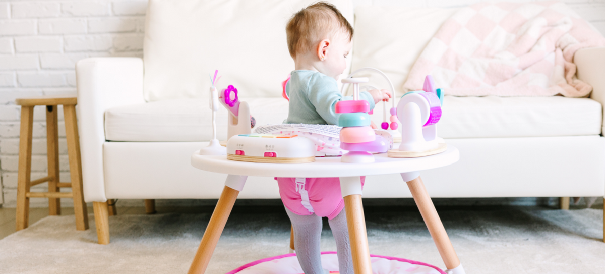 baby sitting in a little acorn activity center - rainbow